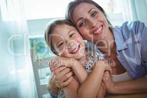 Happy mother and daughter embracing at home