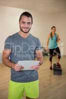 Portrait of smiling fitness trainer holding clipboard
