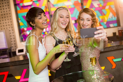 Female friends taking selfie from mobile phone while having champagne