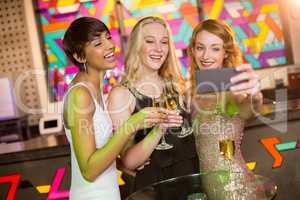 Female friends taking selfie from mobile phone while having champagne