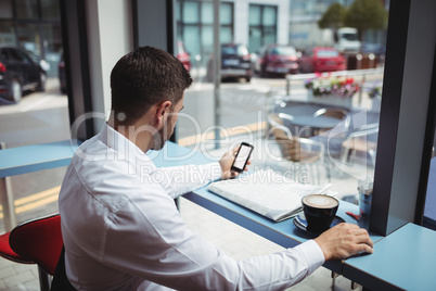 Man using mobile phone while having coffee