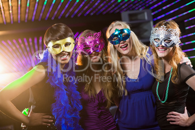 Female friends wearing masquerade in bar
