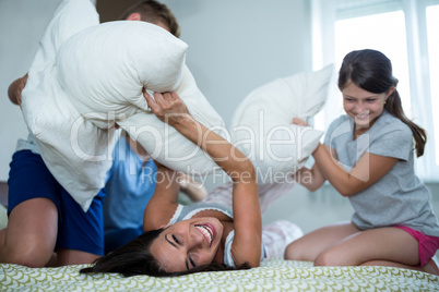 Family having pillow fight in bedroom