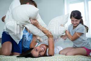 Family having pillow fight in bedroom