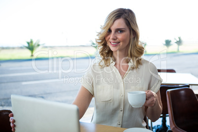 Portrait of woman holding a laptop and coffee cup