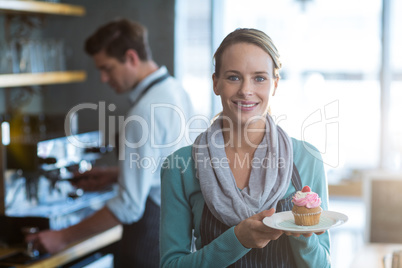 Portrait of waitress holding a plate of cupcake