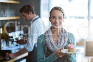 Portrait of waitress holding a plate of cupcake