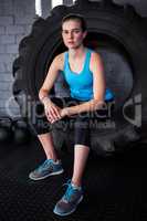 Serious female athlete sitting on tire