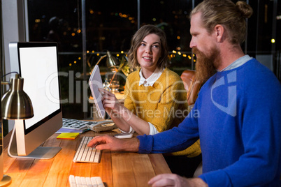 Businesswoman and colleague interacting while working on computer at their desk