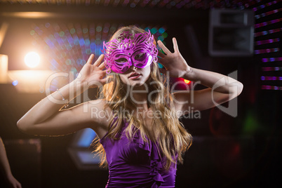 Woman with masquerade dancing on dance floor
