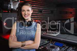 Pretty female DJ standing with arms crossed