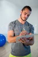 Fitness trainer writing on clipboard