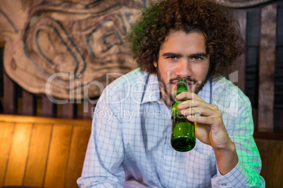 Smiling man having bottle of beer in bar