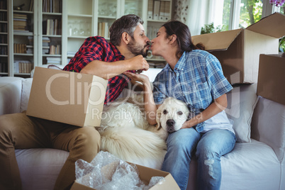 Young couple kissing each other while unpacking carton boxes