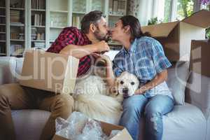 Young couple kissing each other while unpacking carton boxes