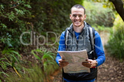Male hiker holding a map in forest