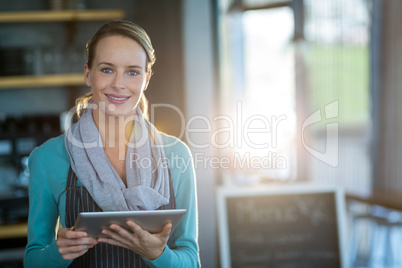 Smiling waitress using digital tablet in cafe