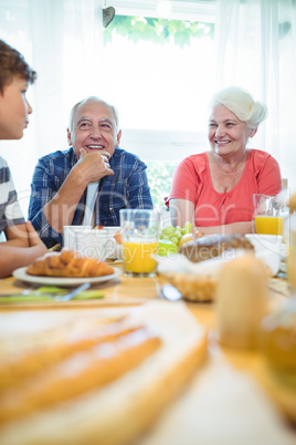 Boy and grandparents sitting at breakfast table