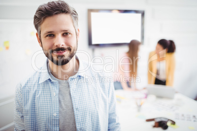 Portrait of confident businessman standing in meeting room at creative office