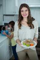 Woman holding a plate of cupcakes
