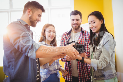 Businessman showing virtual reality headset to coworkers