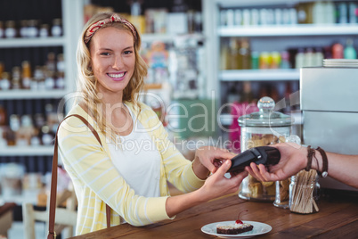 Smiling woman entering pin number into machine at counter