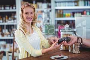 Smiling woman entering pin number into machine at counter