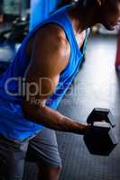 Male athlete exercising with dumbbell in fitness studio