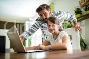 Portrait of father and daughter using laptop in the living room