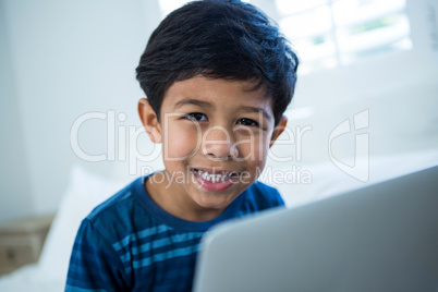Boy using laptop while relaxing on bed