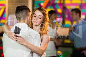 Woman checking her mobile phone while embracing a man