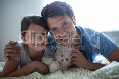 Portrait of father and daughter lying in bedroom