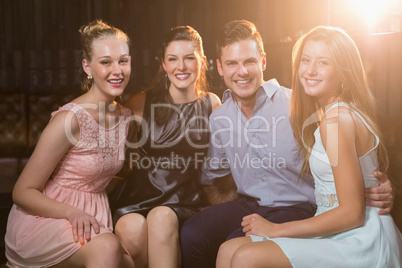 Smiling friends sitting together in sofa at bar