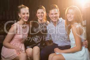 Smiling friends sitting together in sofa at bar