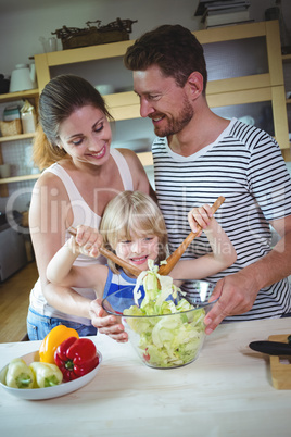 Parents watching their daughter mixing the salad