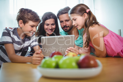 Family using digital tablet while sitting at table