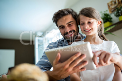 Father and daughter using digital tablet in the living room