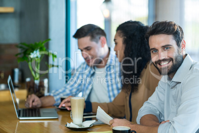 Smiling man in cafÃ?Â© with friends in background