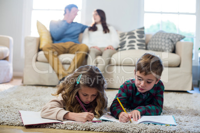 Children doing homework with parents in background