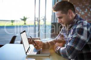 Man using mobile phone with laptop on table