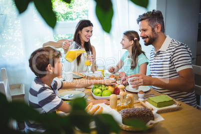 Happy family talking to each other while having breakfast together