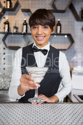 Waitress holding glass of cocktail in bar counter