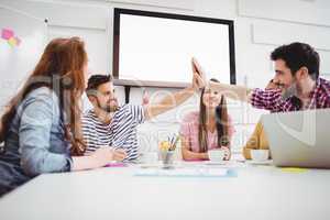 Male colleagues giving high-five in meeting at creative office