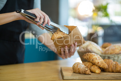 Waitress packing croissants in paper bag at cafÃ?Â©