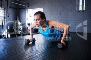 Sporty young woman holding dumbbells in gym