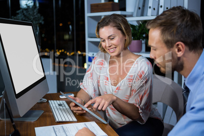 Businesswoman discussing with colleague over digital tablet