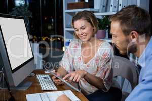 Businesswoman discussing with colleague over digital tablet