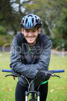 Male athletic standing with mountain bike in park