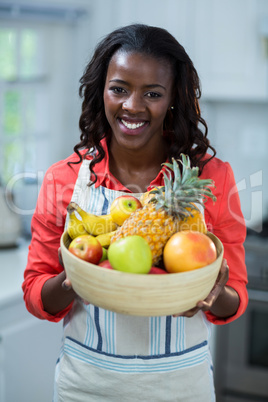 Portrait of woman holding bowl of fruits