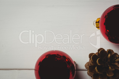 Red christmas bauble and pine cone on wooden table